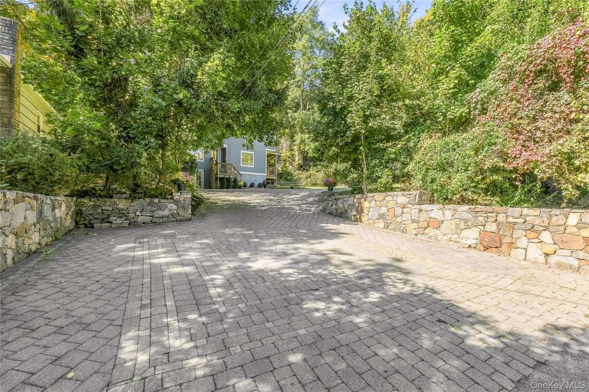 Paver driveway framed by natural stone retaining walls offering plenty of parking