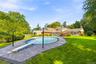 Backyard grounds featuring an inground swimming pool with a diving board, surrounding paver patio, and expansive lawn area
