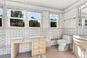 Bathroom featuring floor-to-ceiling decorative tile walls, built-in vanity cabinetry, and three large windows