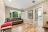 Room featuring wood-finish flooring, a large bay window, and a wide doorway opening to a secondary space