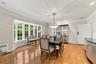 Dining area featuring wood-finish flooring, a multi-pane bay window, crown molding, and an overhead chandelier with crystal accents