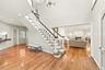 Foyer featuring wood-finish flooring, a two-story ceiling, a staircase with a white spindle railing, and overhead chandelier lighting
