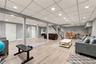 Finished lower level with wood-finish flooring, recessed lighting, vertical paneling, and a staircase featuring wood railings