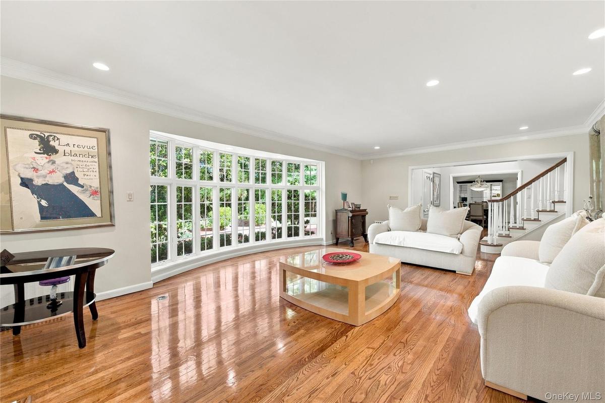 Spacious room featuring wood-finish flooring, recessed lighting, crown molding, and a large multi-pane bay window