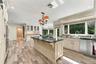 Kitchen featuring custom cabinetry with crown molding, a center island with a dark stone countertop, stainless steel appliances, wood-finish flooring,