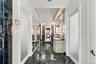 Polished stone flooring, built-in vanity with integrated lighting, full-length mirrored panels, and custom millwork featuring crown molding