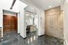 Polished stone flooring, custom floor-to-ceiling cabinetry with ornate detailing, built-in vanity with integrated lighting, and stained wood double do