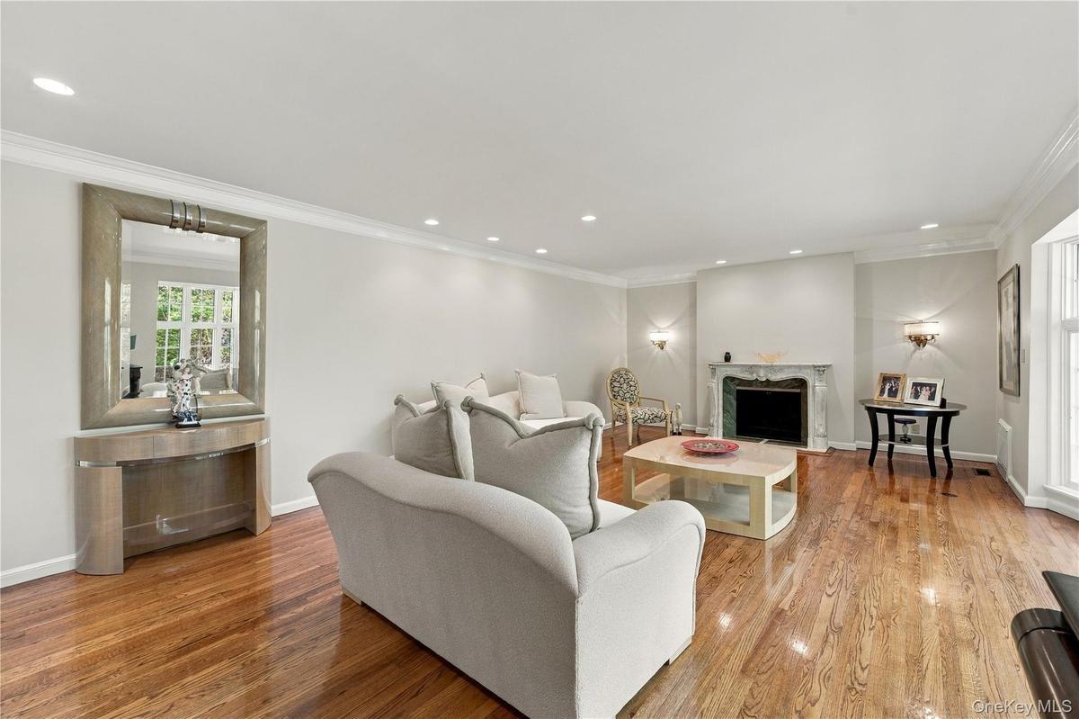 Hardwood flooring, crown molding, recessed lighting, and stone fireplace surround