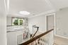 Open landing featuring tiered crown molding, a decorative metal chandelier, arched-panel interior doors, and a curved staircase with a wood handrail