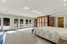 Spacious room with neutral wall-to-wall carpeting, recessed ceiling lighting, three sets of glass patio doors, and built-in wood cabinetry