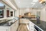Kitchen featuring cream-toned cabinetry with crown molding, dark stone countertops, wood-finish flooring, a stainless steel range with a custom hood e