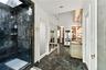 Enclosed shower featuring dark stone tile surround, stone flooring, built-in vanity with integrated lighting, recessed ceiling lighting, and floor-to-