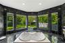 Polished stone wall and floor tiling, expansive multi-panel window configuration, and recessed soaking tub with integrated fixtures