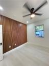 Vertical wood-slat accent wall, light-toned wood-finish flooring, matte black ceiling fan with integrated lighting, and recessed overhead lighting