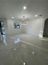 Large-format tile flooring, recessed ceiling lighting, crystal chandelier, and arched doorway entry