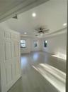 Tray ceiling with recessed lighting, multi-blade ceiling fan, and wood-finish flooring