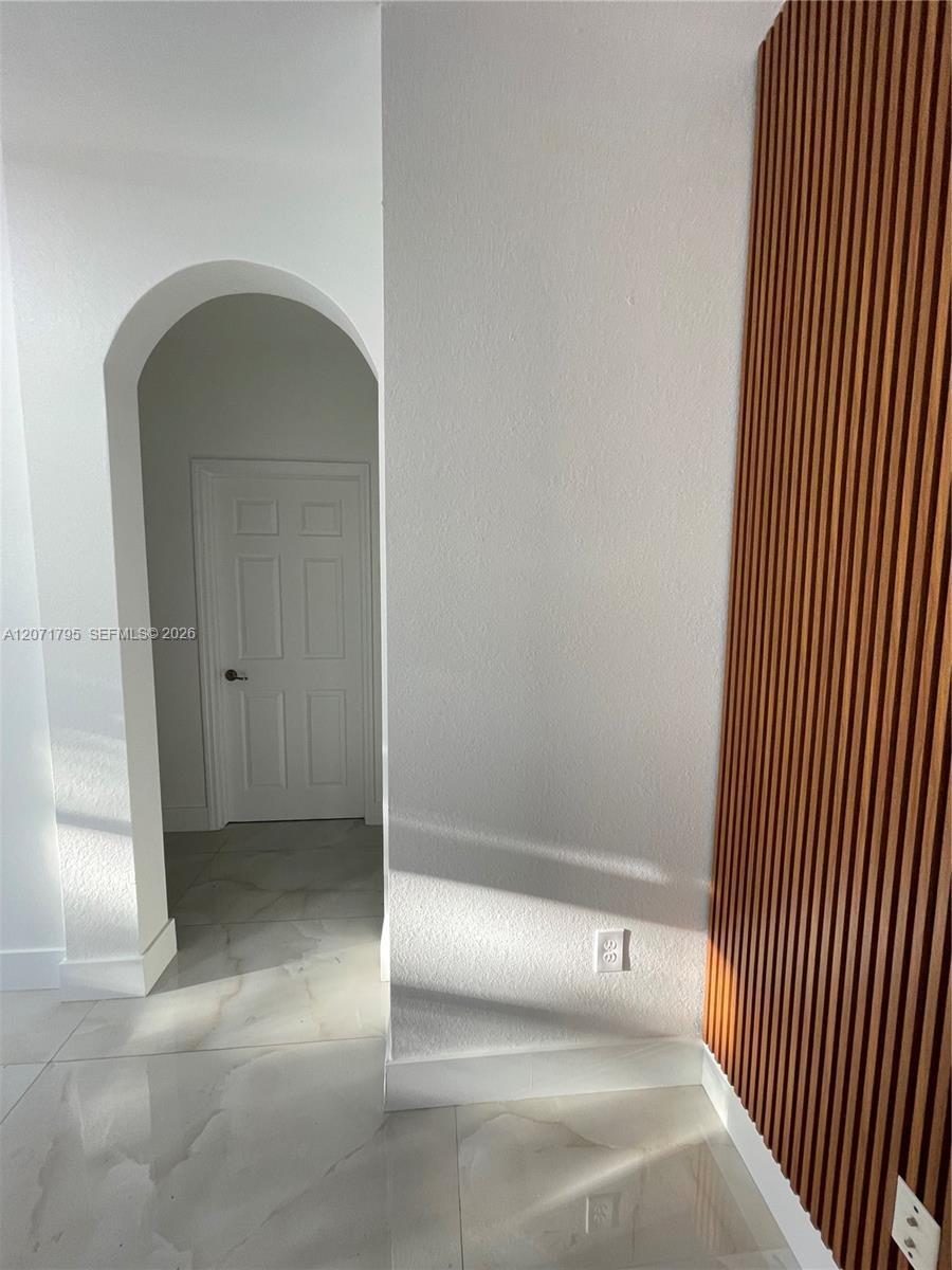 Vertical wood-slat accent wall, arched architectural opening, and large-format tile flooring