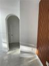 Vertical wood-slat accent wall, arched architectural opening, and large-format tile flooring