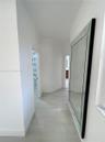 Hallway featuring neutral-toned wood-finish flooring and stark white walls