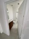 Wood-finish vanity with an integrated sink, polished chrome hardware, wall-mounted globe lighting, and tile flooring
