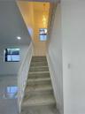 Staircase featuring white balusters and wood-finish treads, complemented by a multi-tiered crystal chandelier, recessed lighting, and large-format til