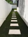 Side yard featuring synthetic turf, concrete paver stones, and white vinyl privacy fencing