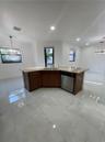 Kitchen island featuring wood cabinetry, stone-finish countertops, stainless steel undermount sink, and integrated stainless steel dishwasher, complem