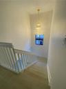 Staircase featuring wood-finish treads, a white wooden balustrade, and a multi-tiered crystal chandelier pendant fixture