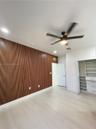 Interior space featuring a slatted wood-finish accent wall, light-toned wood-finish flooring, recessed lighting, and a modern ceiling fan with an inte
