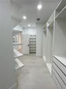 Walk-in storage area featuring custom white built-in shelving, integrated dresser drawers, recessed lighting, and wood-finish flooring