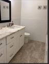 White vanity with a stone countertop, under-mount sink, subway tile wainscoting, and large-format tile flooring