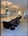 Kitchen featuring a large central island with stone-surface countertop, dark-finish cabinetry, ornate hanging pendant lighting, and polished stone-fin