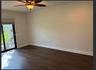 Wood-finish flooring, sliding glass door with integrated blinds, and ceiling fan with integrated light fixture
