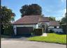 Stucco exterior residence featuring a multi-gabled tile roof, an arched covered entryway, and a paved walkway