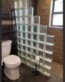 Glass block privacy partition, textured stone-finish wall, dark oversized tile flooring, and a single-hung window