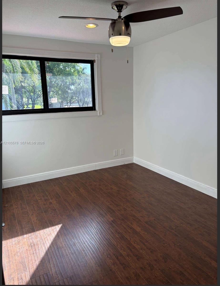 Room featuring wood-finish flooring, a ceiling fan with integrated lighting, recessed lighting, and a window with dark-toned trim