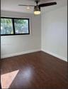 Room featuring wood-finish flooring, a ceiling fan with integrated lighting, recessed lighting, and a window with dark-toned trim