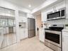 Kitchen featuring white shaker cabinetry, stainless steel appliances, light-toned tile flooring, white subway tile backsplash, and light-toned counter