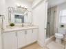 Bathroom featuring a white vanity with a stone countertop, an undermount sink, a framed mirror, and a glass-enclosed shower with tiled walls