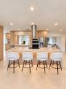 Kitchen featuring a central island with integrated cooktop, stone-finish countertops, stainless steel cylindrical range hood, custom wood-finish cabin
