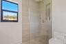 Walk-in shower featuring floor-to-ceiling tile, a glass partition, a built-in recessed niche, and gold-finish hardware including a rainfall showerhead