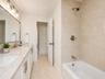 White vanity with brushed nickel hardware, a rectangular undermount sink, and a stone countertop