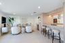 Open-concept space featuring light-toned cabinetry, a stone-surface breakfast bar with under-cabinet lighting, recessed ceiling lights, and tile floor