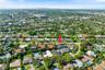 Aerial perspective of a residential property featuring a low-pitch roof, a multi-car driveway, and mature landscaping