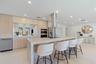 Contemporary kitchen featuring a large waterfall-edge island with light stone countertops, stainless steel appliances including a built-in double oven