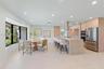 Modern kitchen featuring light wood-finish cabinetry, a large stone-surfaced island with a cylindrical exhaust hood, stainless steel appliances, reces
