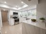 Modern kitchen featuring white cabinetry, stainless steel appliances, a breakfast bar, and multiple windows with blinds
