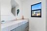 Wall-mounted vanity with solid-surface countertop, integrated rectangular sink, brass-finish faucet, organic-shaped mirror, and black-framed window