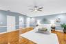 Exquisite primary bedroom suite featuring dual expansive walk-in closets, vaulted ceilings, a dedicated sitting area, hardwood flooring, and a private