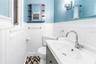 This is the second bedroom's half bath, featuring charming beadboard paneling and elegant fixtures.